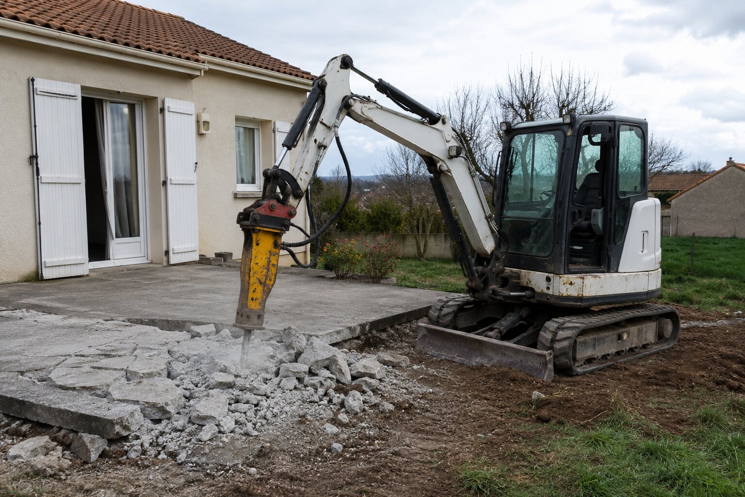 Mini-pelle équipée d’un BRH cassant une terrasse en béton